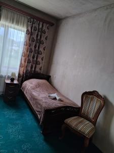a bedroom with a bed and a chair and a window at Garni Guesthouse in Garni