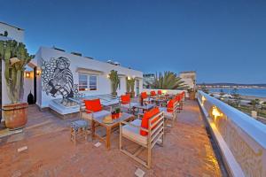 un patio con sillas naranjas y mesas en el techo en Madada Mogador, en Essaouira