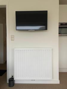 a flat screen tv hanging on a wall with a radiator at Studio Suite Lido in Koksijde