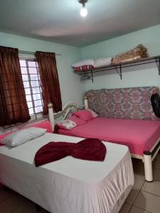 two beds in a room with pink and white sheets at Apartamento1 beto carreiro cozinha compartilhada in Penha