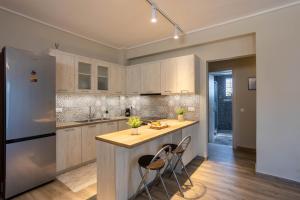 a kitchen with white cabinets and a island with chairs at Luxury & Cozy apartment in Messini