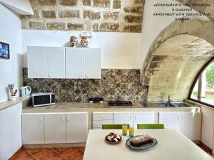 Il Giardino Sulla Valle في راغوزا: مطبخ فيه دواليب بيضاء وطاولة عليها كيكة