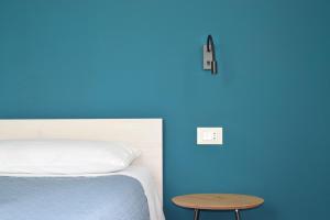 ein Schlafzimmer mit einer blauen Wand, einem Bett und einem Tisch in der Unterkunft VESPRI 15 apartments in Trapani