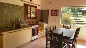 uma cozinha com uma mesa, um lavatório, uma mesa e cadeiras em Casa con jardín, pileta, asador, y vistas al lago en Embalsina em Villa del Dique
