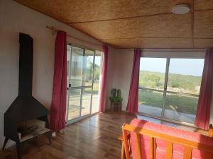 uma sala de estar com lareira e janelas grandes em Las Carobas em Minas