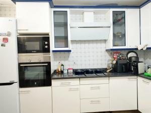 una cocina blanca con armarios y electrodomésticos blancos en Castro-urdiales Apartamento compartido o entero, en Castro Urdiales