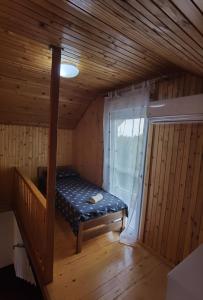 Habitación pequeña con cama en una cabaña con ventana en Kuća za odmor Bella, en Sotin