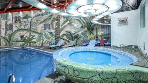 La salle de bains est pourvue d'une baignoire jacuzzi et d'une fresque murale. dans l'établissement Suites Inn la Muralla Hotel & Spa, à Toluca