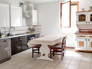 une cuisine avec une table et des chaises et une cuisine avec des placards blancs dans l'établissement Immersa nel verde, à Venise