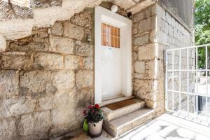 a stone building with a white door and a potted plant at Apartment Giardino in Split
