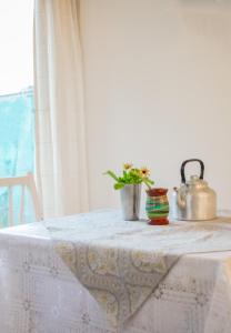 a table with a white table cloth with a tea kettle and a plant at La serena in San Carlos de Bariloche
