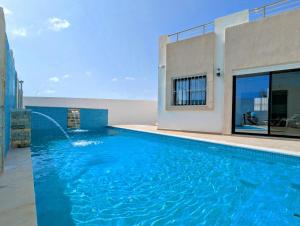 a swimming pool in front of a house at Villa NIÇOISE DJERBA in Awlād ‘Umar