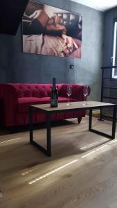 - une table avec deux verres à vin et un canapé rouge dans l'établissement FOXYROOM, à Le Petit-Quevilly