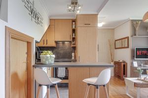 eine Küche mit zwei weißen Stühlen und einer Theke in der Unterkunft San Amaro Beach 1 by TheBlueWaveApartments com in A Coruña