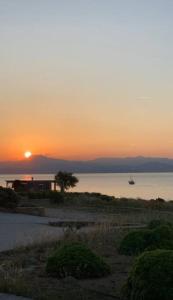 a sunset over the ocean with a boat in the water at Mini Beach House in Logaras