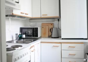 a kitchen with white cabinets and a stove top oven at City Center Coziest Studio in Tampere