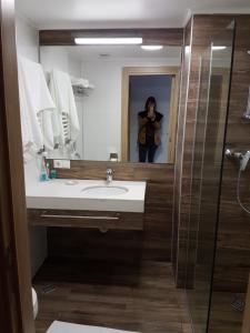 a woman taking a picture of a bathroom mirror at ORBI PALACE room 556 in Bakuriani