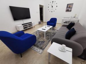 ein Wohnzimmer mit einem Sofa, Stühlen und einem TV in der Unterkunft Khan Property in Schardscha