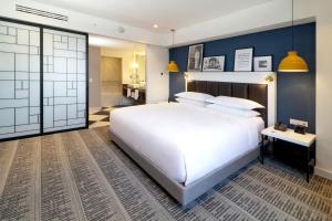 a bedroom with a large white bed and a bathroom at Culiacan Marriott Hotel in Culiacán