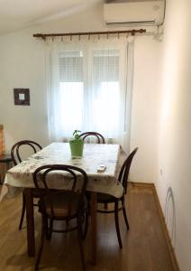 una mesa de comedor con sillas y una planta en Vukčević apartman, en Sutomore