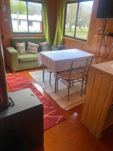 a living room with a table and a couch at Cabaña las gotas coñaripe in Coñaripe