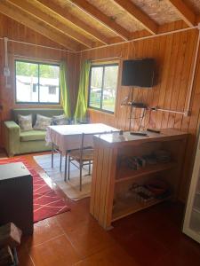 a living room with a table and a couch and a television at Cabaña las gotas coñaripe in Coñaripe +3 photos