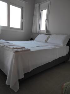 um quarto com uma grande cama branca e 2 janelas em GERAKOFOLIA-VILLA em Nikiana