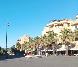 a large building with palm trees in front of it at Attico con terrazza in Via dei Traghetti in Lido di Ostia