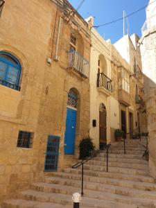 a stone building with a blue door and stairs at Tifkira (The Memory) in Birgu