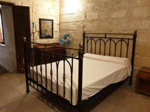 ein schwarzes Bett in einem Zimmer mit einer Steinmauer in der Unterkunft Tifkira (The Memory) in Vittoriosa