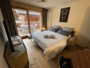 a bedroom with a bed with a television and a window at GESPERE LE STELLA in Les Gets