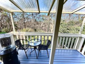 eine Veranda mit einem Tisch und Stühlen auf einer Terrasse in der Unterkunft Blissful Mountain Stay in Katoomba