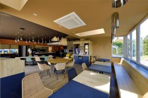 um restaurante com mesas e cadeiras azuis e uma cozinha em Sure Hotel by Best Western Dole em Dole