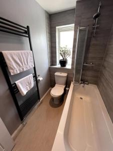 ein Bad mit einer Badewanne, einem WC und einem Fenster in der Unterkunft Thistle House - hot tub, parking in Kent