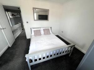 ein weißes Bett in einem Zimmer mit Spiegel in der Unterkunft Thistle House - hot tub, parking in Kent
