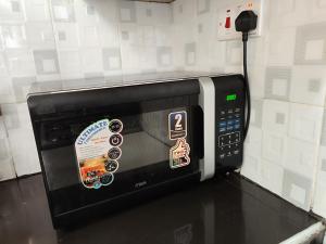 a black microwave with stickers on it in a kitchen at Pine Residency Homestay in Kikuyu