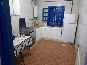 Harqalah的住宿－Maison à Hergla, Sousse, Tunisie，厨房配有白色冰箱和桌椅