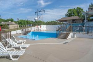 a swimming pool with white chairs and a slide at StoneBridge Village Resort in Reeds Spring
