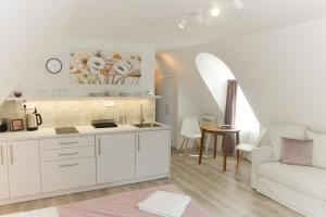 cocina y sala de estar con armarios blancos y sofá en Raba92 Apartman House, en Győr