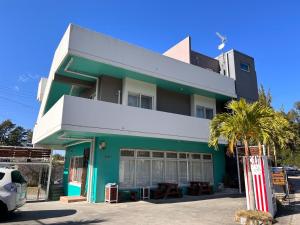 a green and white building with a palm tree at Ocean Villa Tin Gala - Vacation STAY 98840v in Atsutabaru