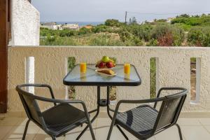 una mesa con fruta y 2 sillas en el balcón en Sofia's Apts en Hersonissos