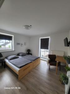 a bedroom with a bed and a table and two windows at Beautiful Cozy apartments close to lakes and nature parks in Schwandorf in Bayern