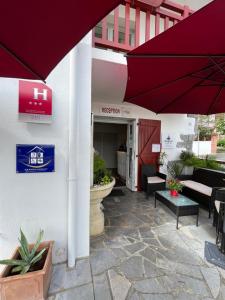 une terrasse avec des parasols rouges en face d'un bâtiment dans l'établissement Hôtel Ursula, à Cambo-les-Bains