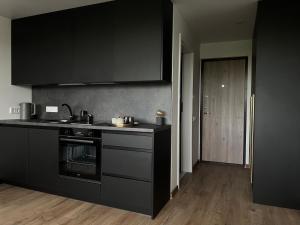 a kitchen with black cabinets and a stove top oven at 111 Studio Apartment near Old town in Klaipėda