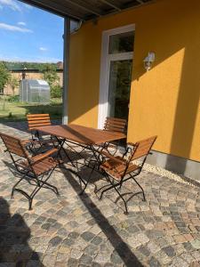 einen Holztisch und Stühle neben einem gelben Gebäude in der Unterkunft Ferienwohnung Malisa in Bad Bibra