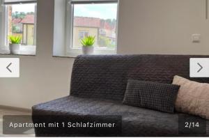 ein Sofa im Wohnzimmer mit zwei Fenstern in der Unterkunft Ferienwohnung Malisa in Bad Bibra