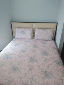 a bed with a pink comforter and two pillows at Elsa's House in Arta