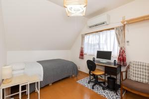 Schlafzimmer mit einem Bett und einem Schreibtisch mit einem Computer in der Unterkunft Hiei Blue Roof - Vacation STAY 13887 in Ōtsu