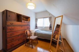 Schlafzimmer mit einem Bett, einer Kommode und einem Spiegel in der Unterkunft Hiei Blue Roof - Vacation STAY 13887 in Ōtsu