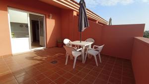 een patio met een tafel en stoelen en een parasol bij Vacacional Montañés in El Matorral